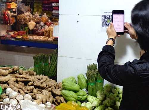 市平易近在菜市场买菜用手机付出。（《日本经济消息》网站）